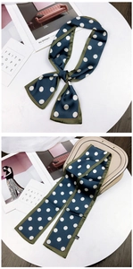 Detail of navy blue silk twilly scarf with white polka dots and green border edge