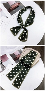 Deep green polka dot silk scarf tied on a beige handbag with stylish neck wrap detail