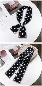 Polka dot twilly silk scarf tied in a bow and wrapped on a beige handbag handle