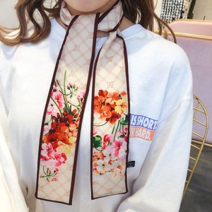 Detailed close-up of a floral print silk twilly scarf with elegant geometric patterns