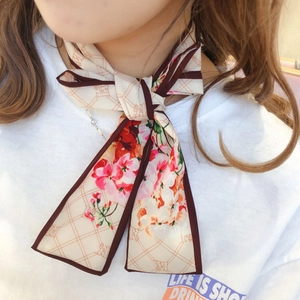 Detail of floral printed twilly scarf tied in a bow showing cherry blossom pattern