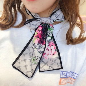 Close-up of floral print long neck scarf tied in a bow over a white casual t-shirt