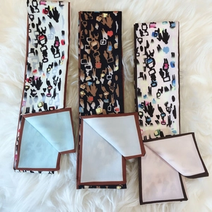Three premium printed twilly scarves with abstract art patterns on soft plush surface