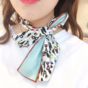Close-up of printed long silk scarf tied in a bow showing abstract patterns and satin sheen