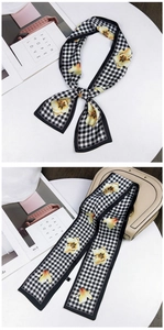 Close-up of houndstooth silk scarf with orange tulips tied on a beige leather handbag