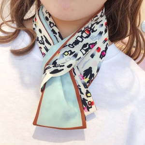 Close-up of a leopard print silk twilly scarf styled as a neck tie over a white t-shirt