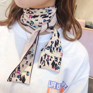 Close-up of a pink long skinny scarf with pop art print worn around the neck
