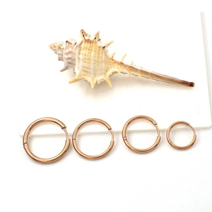 Set of four rose gold stainless steel hoop earrings in various sizes with conch decoration