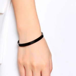 Detailansicht eines schwarzen minimalistischen Armreifs am Handgelenk getragen