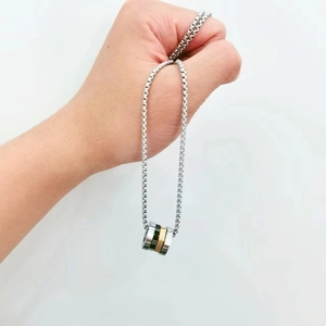 Detail of three-tone stainless steel rings pendant with Roman numerals on a box chain
