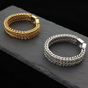 Gold and silver double-row braided stainless steel Cuban bracelets on black stone slab