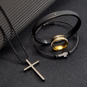 Detalle de collar de cruz, brazaletes y anillo de acero inoxidable negro mate