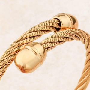 Golden twisted cable wire bracelet with polished metal end caps for a modern punk look