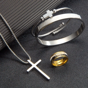Vista macro de conjunto de joyas religiosas de acero con grabados y anillo de números romanos