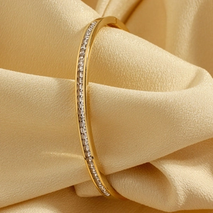 Elegant gold-plated bangle with square cubic zirconia stones on silk fabric