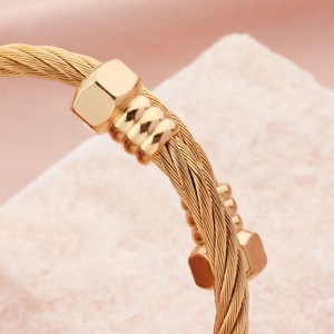 Gold braided stainless steel cable bracelet with hexagonal nut accents in industrial style