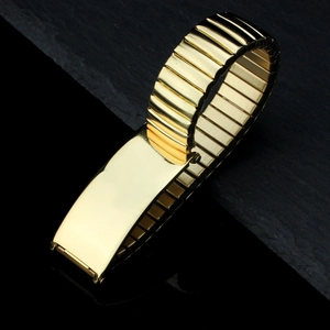 Polished gold stainless steel elastic watch band bracelet on a black stone background