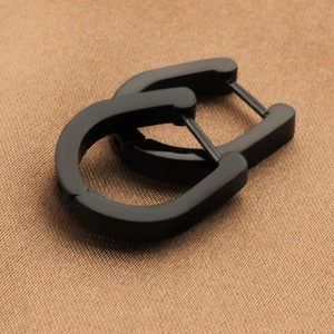Minimalist matte black U-shaped titanium steel hoop earrings on textured brown fabric