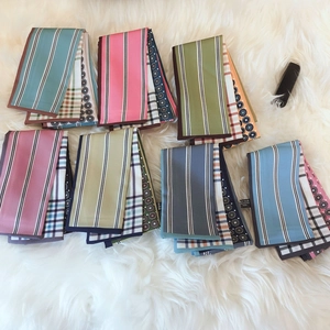 Collection of skinny silk scarves featuring stripes and polka dots on plush white carpet