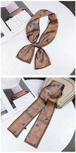 Detail of floral and houndstooth pattern silk scarf tied on a beige handbag handle