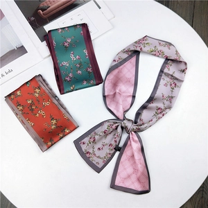 Detailed display of colorful floral silk-feel twilly scarves on a white minimalist table