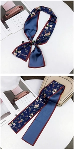 Detail of floral silk scarf tied to a beige handbag with high gloss and smooth texture