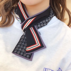 Close-up of elegant black floral twilly scarf tied around neck with red border detail