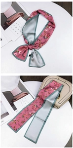 Detailed view of pink floral twilly scarf tied on a light handbag with double-sided design