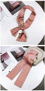 Detailed view of polka dot silk scarf tied as a bow on a beige handbag handle