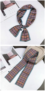 Detail view of multi-color houndstooth narrow scarf with light blue edging on white desk