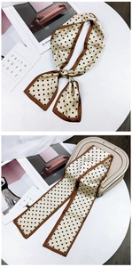 Close-up of polka dot silk scarf tied on a luxury beige leather handbag for women