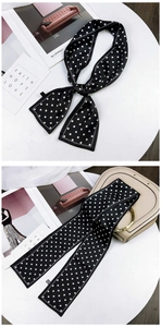 Macro detail of the white polka dot pattern and stitching on the black silk scarf ribbon