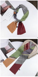 Detail of floral and houndstooth silk scarf tied on a beige handbag with modern props