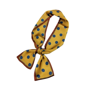 Mustard yellow polka dot twilly silk scarf styled in a bow on a white background