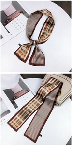 Detail of houndstooth silk scarf tied on a beige handbag with a stylish vintage pattern