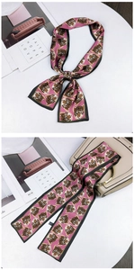 Detail of pink silk scarf with tiger prints used as a chic handbag accessory or hair tie