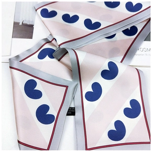 Detailed close-up of a striped silk scarf featuring blue heart patterns and stitching