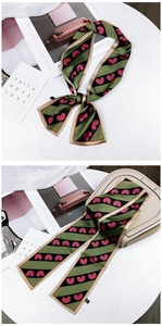 Detail of green striped silk scarf with pink hearts tied on a handbag handle