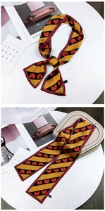 Detail of a yellow and black striped silk scarf twilly with red heart patterns and faith text