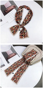 Detail view of caramel brown owl pattern silk scarf tied on a beige handbag handle