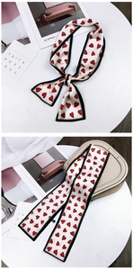 Close-up of cream twilly scarf with red heart patterns tied on a handbag handle