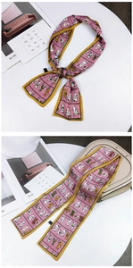 Pink ribbon scarf with cartoon cat print and mustard yellow edges on a white desk