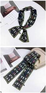 Detail of dark green skinny scarf with cat print tied on a beige handbag handle