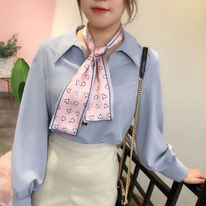 Foulard étroit rose à motif cœur noué sur un col de chemise bleue au style élégant