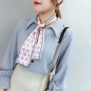 Détail du foulard twilly en soie rose avec motifs de cœurs noué autour du cou