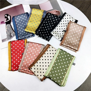 Multiple colorful polka dot scarves arranged in a fan shape on a minimalist white surface