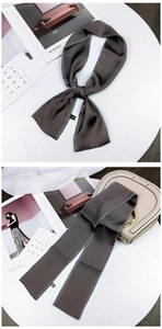Detailed view of brown silk scarf tied on bag handle and in a stylish knot design