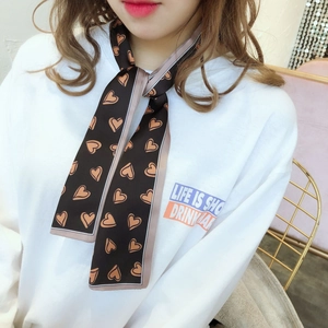 Détail d'un foulard en soie marron double face avec motifs de cœur porté au cou