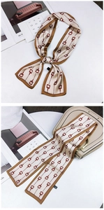Detail of a beige animal series twilly scarf tied on a handbag with chain pattern