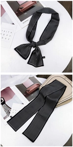 Detail of a thin black and white striped silk scarf styled on a table for fashion
